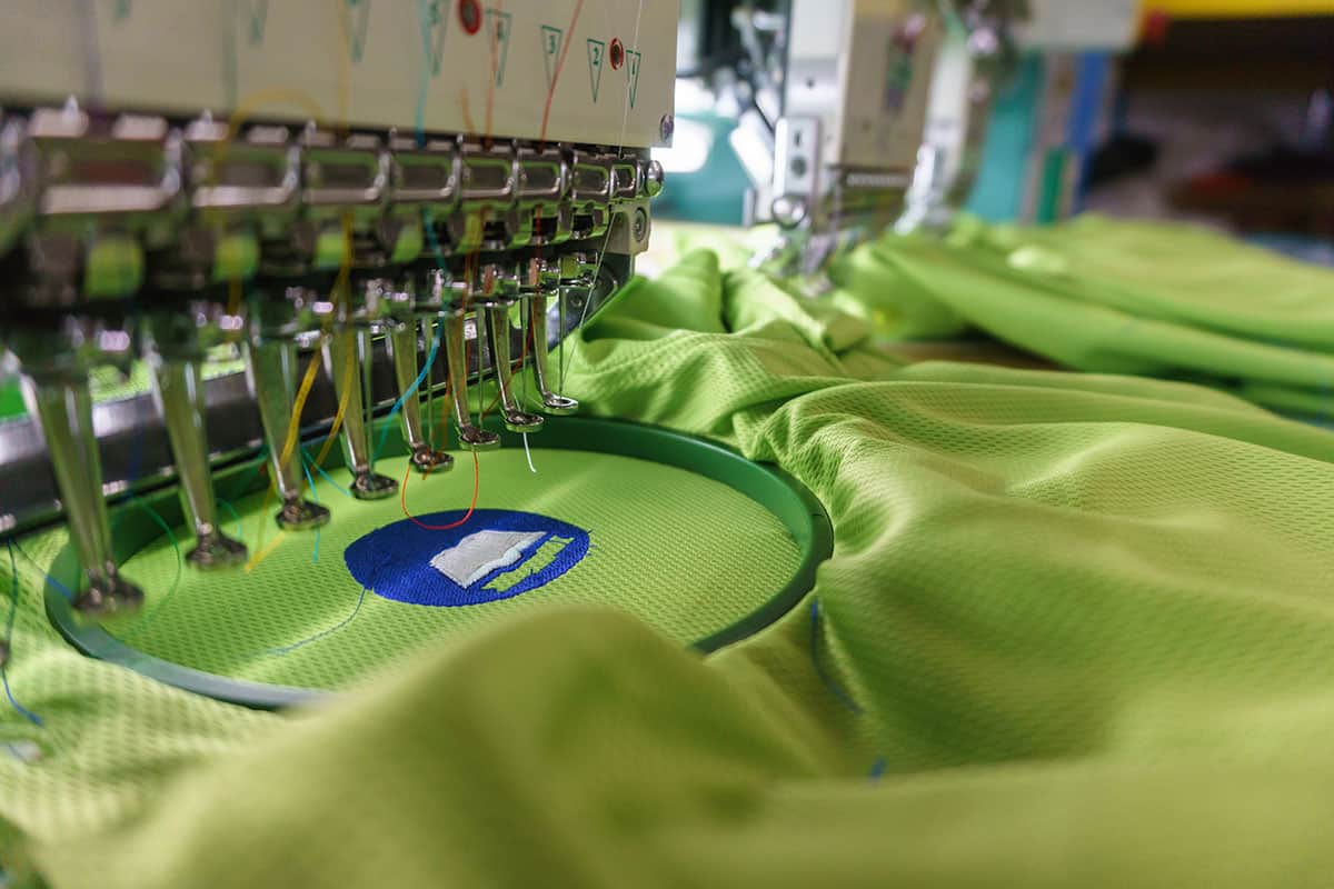 machine-embroidery-process Embroidery machine creating Green Rivercity Screenprinting logo on lime green fabric.